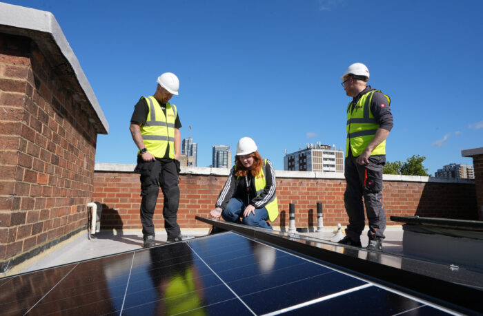 three operatives installing solar panels on a roof