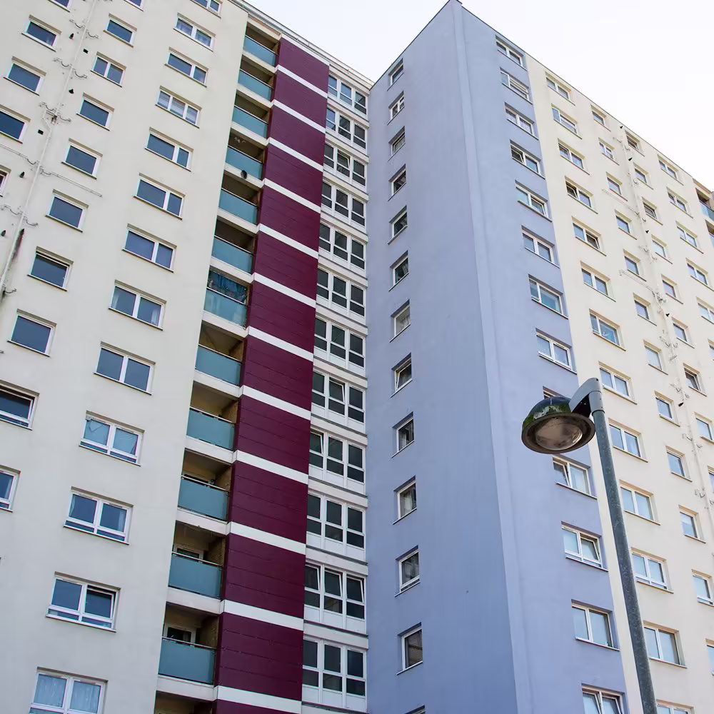 A low-angle shot looking up the facade of a newly re-clad Gosport tower, showing the pattern of white, maroon, and blue cladding panels.