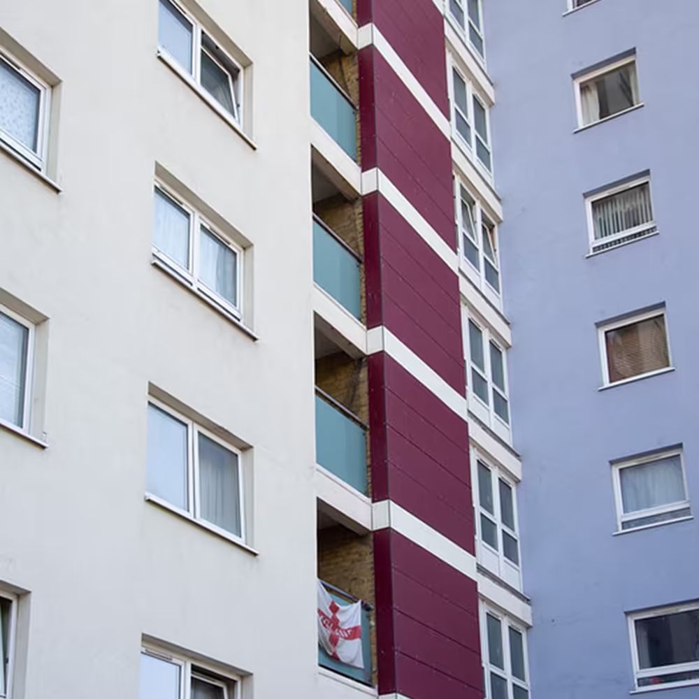 A close-up detail of the new cladding on a Gosport tower, showing the junction between the maroon and white panels next to the residents' balconies.