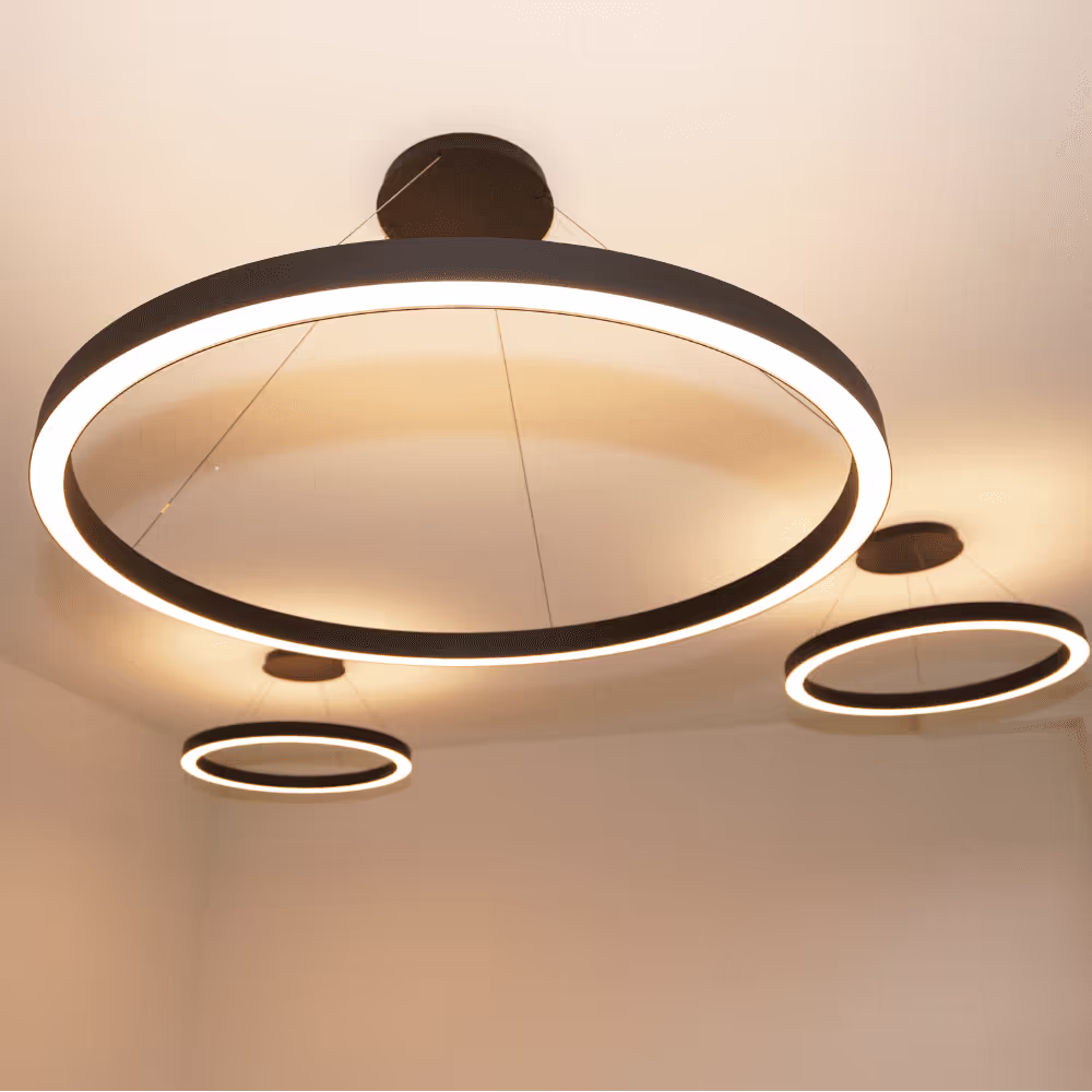 A cluster of contemporary black circular LED halo pendant lights of various sizes, suspended from a white ceiling as part of a modern office refurbishment lighting scheme.