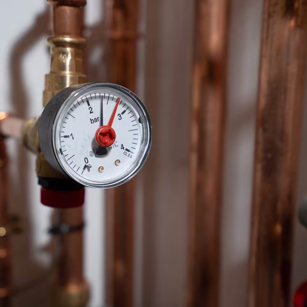 A macro shot of a pressure gauge on the copper pipework of a residential heating system, showing the system is correctly pressurised.